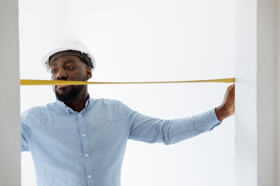 Contractor carefully measuring a window frame for a double hung installation